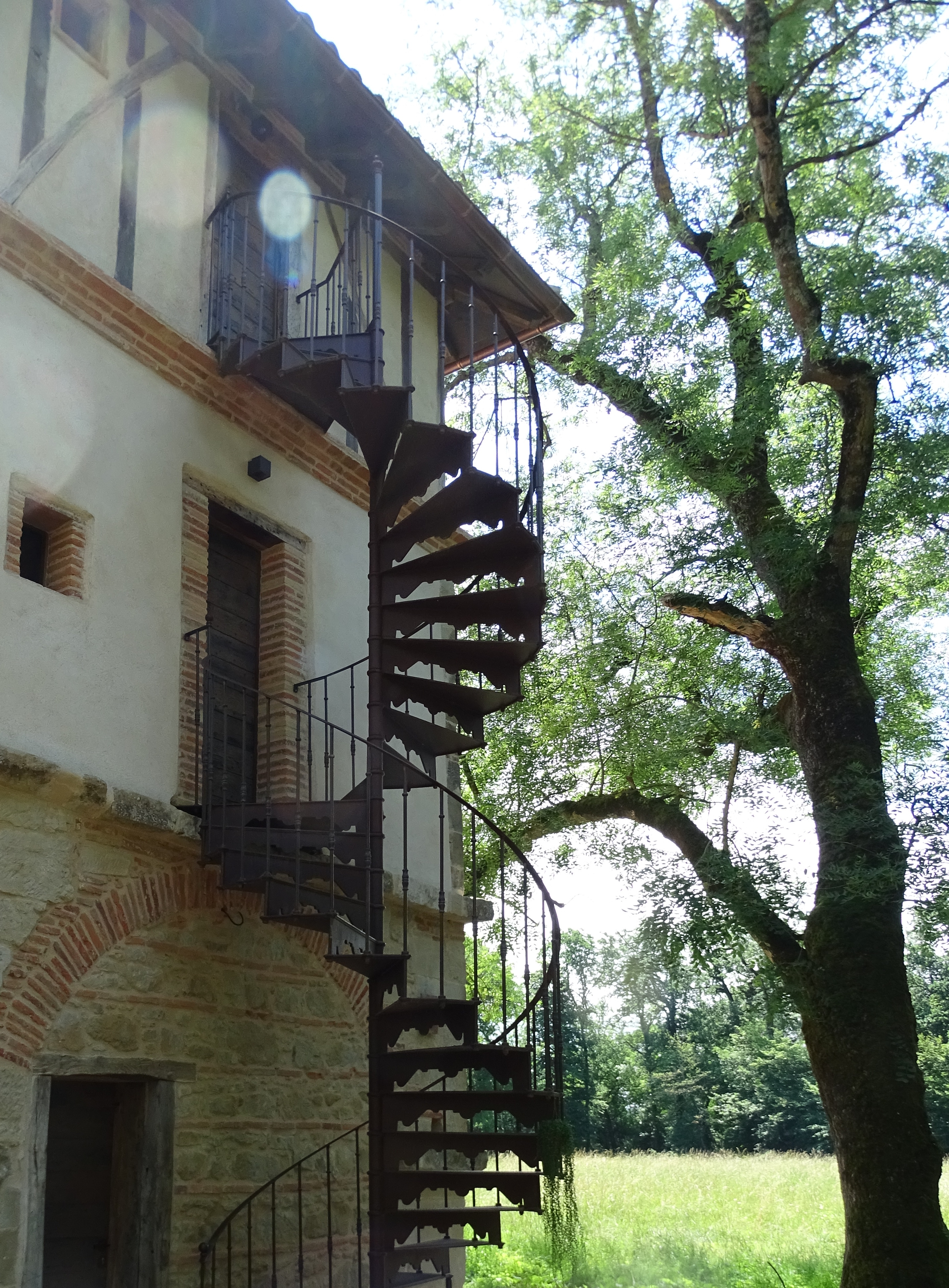 Cast iron spiral staircase model Versailles installed against a dovecote in the Tarn (France)